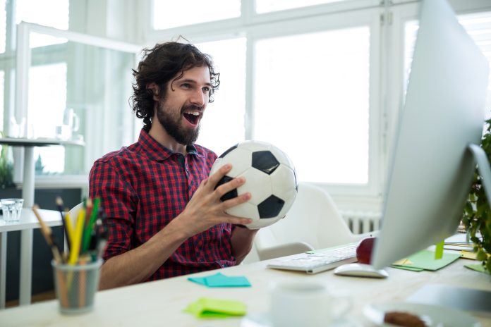 Male graphic designer cheering while watching football match