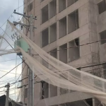 Vento solta tela de obra e material fica preso na rede elétrica em Avenida de Botucatu